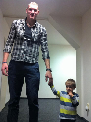 giant man holds hands with cute little kid